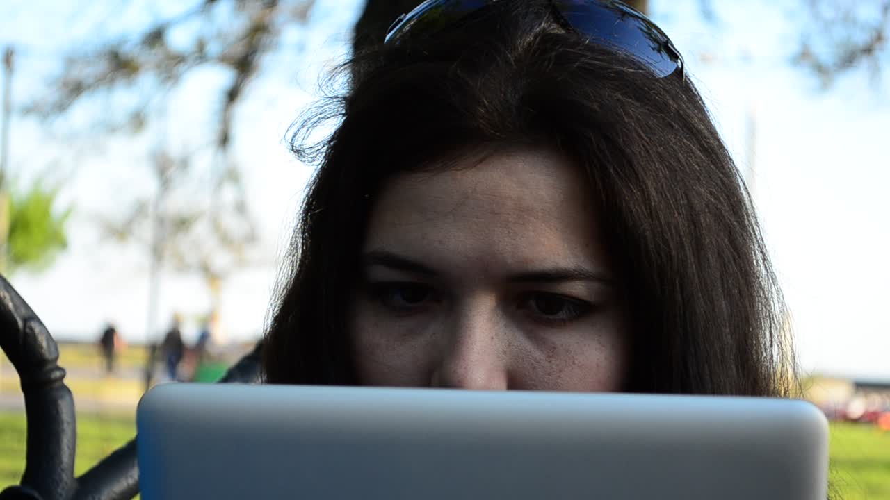 The business girl works with the tablet. The girl with the tablet on a bench