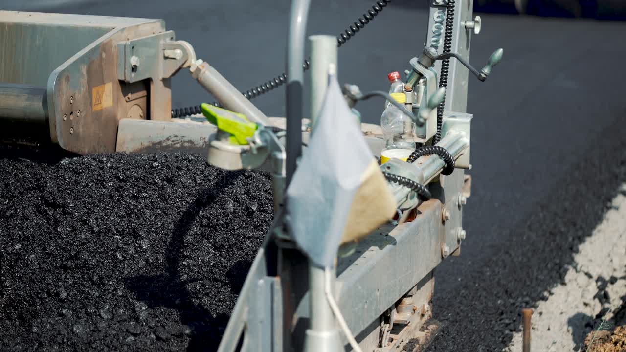 road machinery for leveling the ground passes the road under the supervision of workers. Close-up