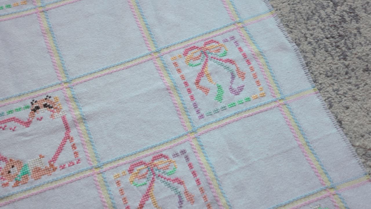 Slow panning shot showing the designs on a cross-stitched baby blanket
