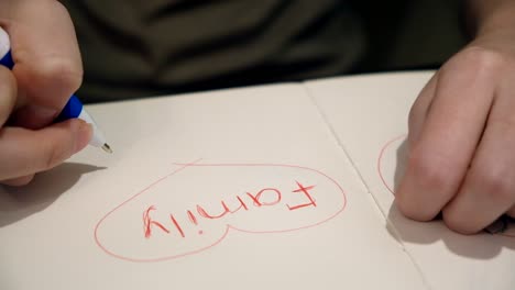 child writing 'family' in a notebook