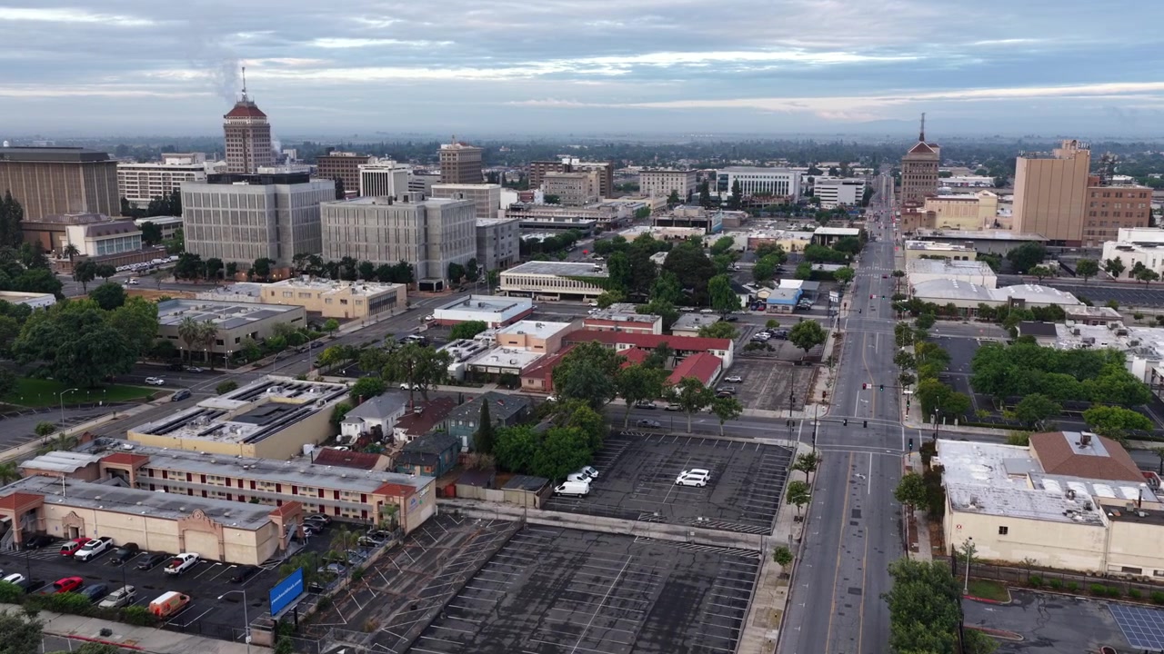 El horizonte de Fresno se eleva sobre el Valle Central de California, con amplios bulevares, estacionamientos, edificios de uso mixto y cielos nublados sobre el centro de Fresno, California, EE. UU. Toma aérea de dron de gran angular