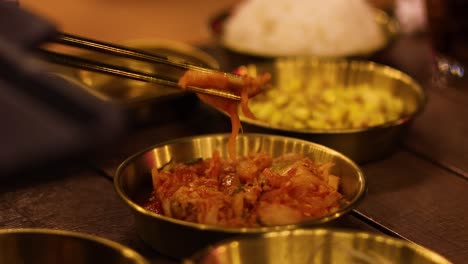 chopsticks picking up kimchi from a bowl