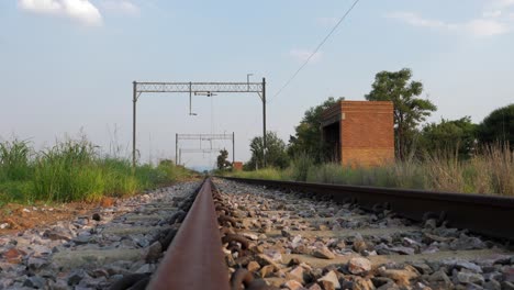 View-down-rusty-railroad-track-with-old-shelter-in-rural-South-Africa