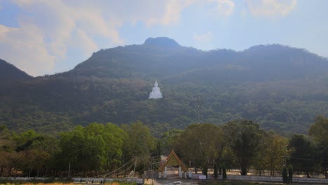 luang por khao, wat theppitak punnaram, descending aerial footage of the famous white temple on the mountain revealing the arch gate, street lights, road going inside, landscape as a whole