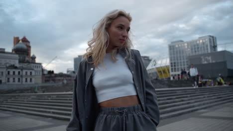 Blonde-city-girl-posing-for-camera-with-smile-in-downtown-street.