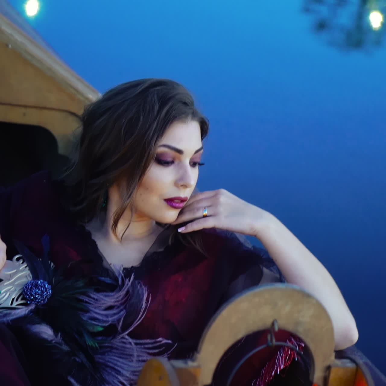 Attractive young woman with bright make-up lying in a boat at night and dreams about love. Sexy girl floating in a gondola on the blue water