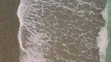 Slow-Motion-Aerial-View-of-Ocean-Waves-Along-Looc-Bay's-Coastal-Beach-with-Turquoise-Waters,-Philippines