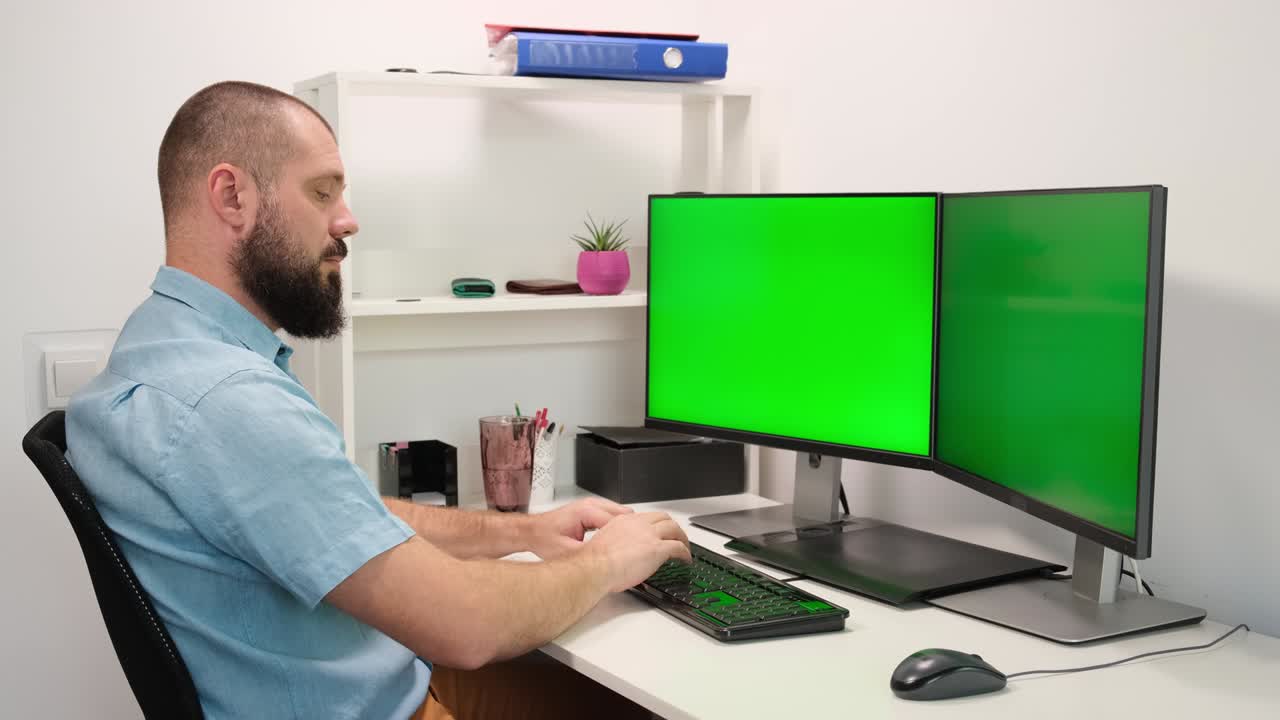 hombre escriba en el teclado en dos monitores con la pantalla verde.