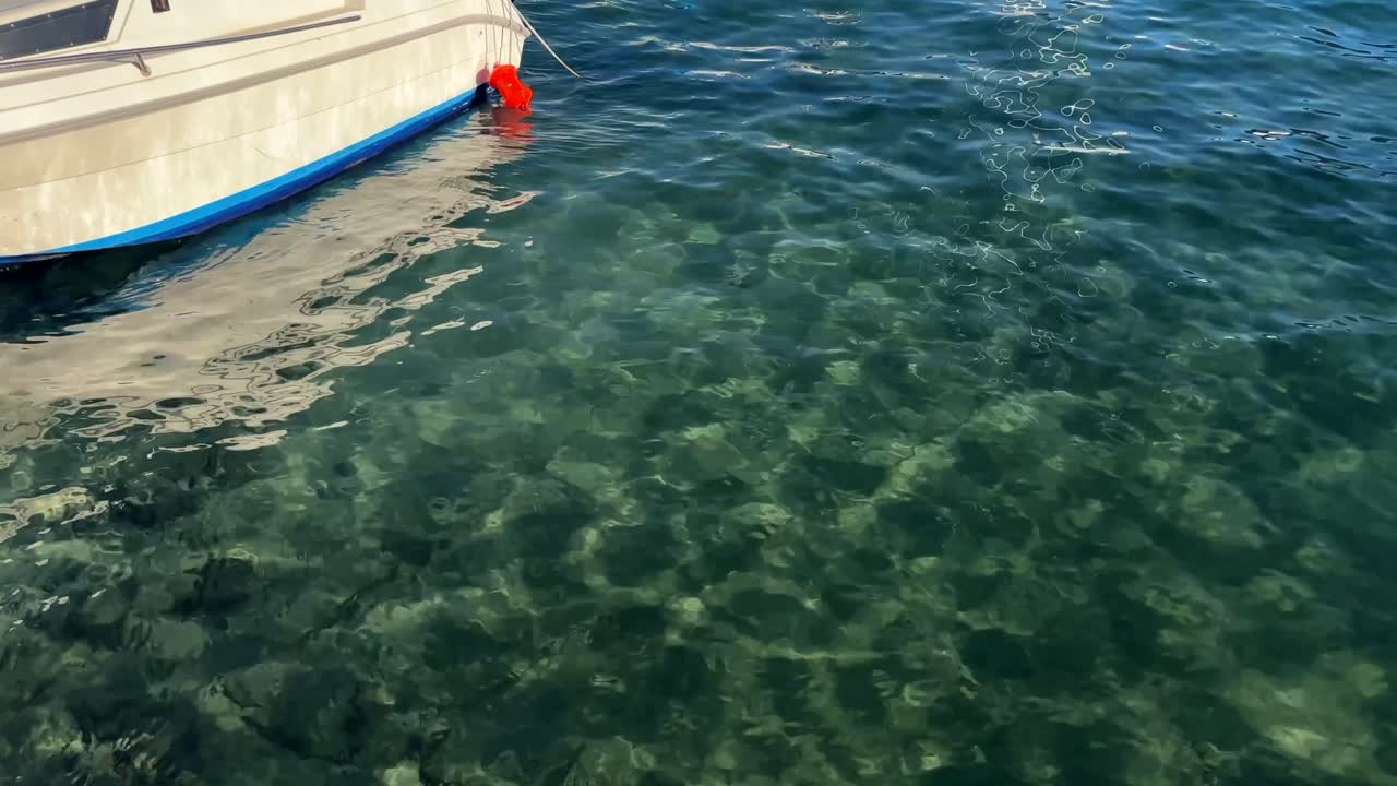 Transparent greenish-blue waters with a moored boat floating on the surface