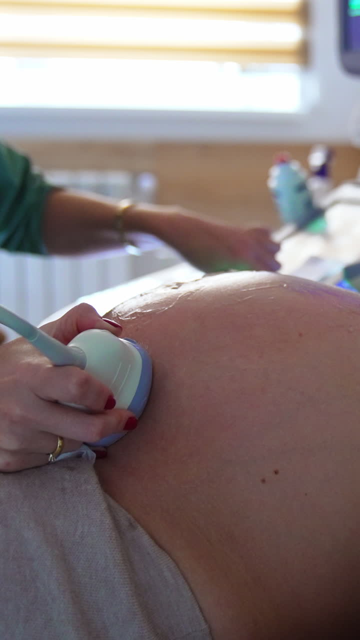 Pregnant lady with big belly is at obstetrician's check. Doctor is doing ultrasound scanning for future mom. Vertical video