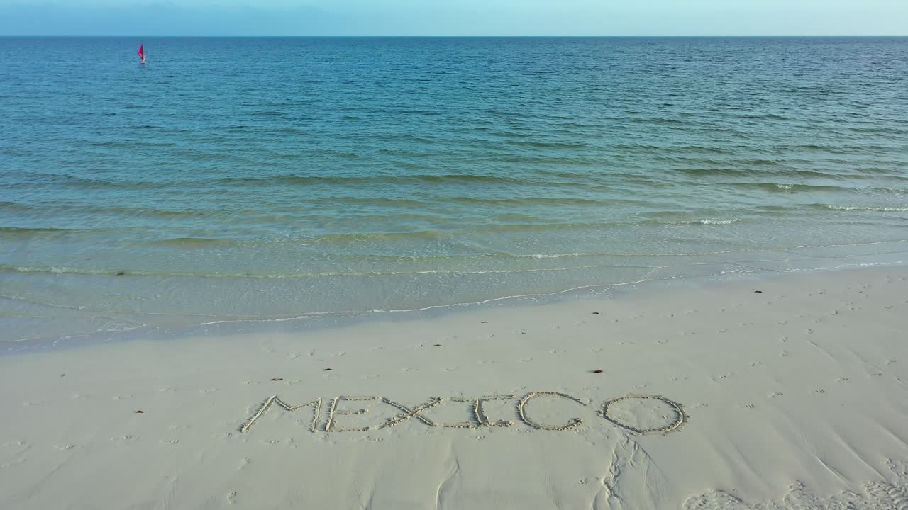 수평선에 윈드서퍼가 있는 해변의 모래에 새겨진 멕시코의 광각 샷