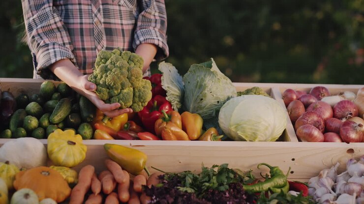 Farmer holds broccoli over a counter at a farmers' fair