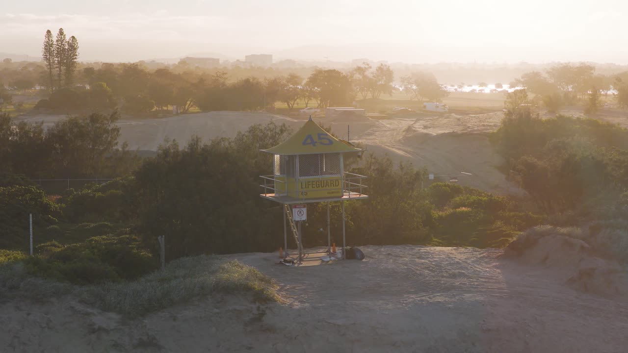 A serene sunset view of a lifesaving tower on Gold Coast, Australia, with warm lighting and tranquil surroundings