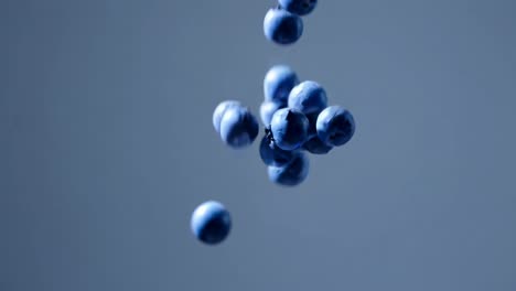 close-up video of blueberries falling against a blue background, captured from a low angle
