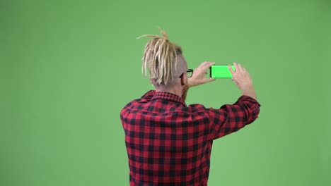 rear view of bearded hipster man with dreadlocks taking picture with phone