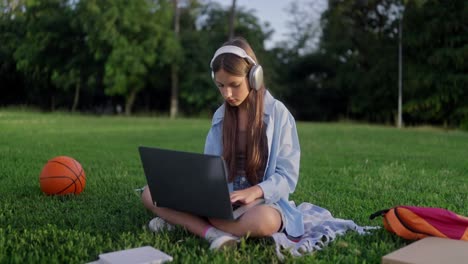 young girl studying on her laptop in a park