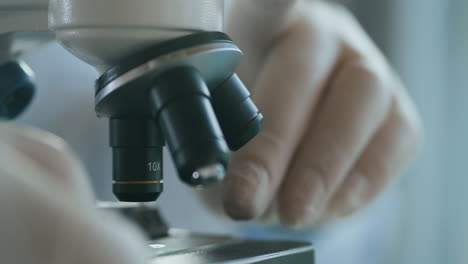 close up of microscope oculars being directed at a sample on a piece of glass. close-up shot of sample slide and microscope with metal lens at laboratory. high quality 4k footage