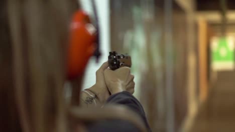 Woman&#039;s hands holding gun, targeting in range and making few shots