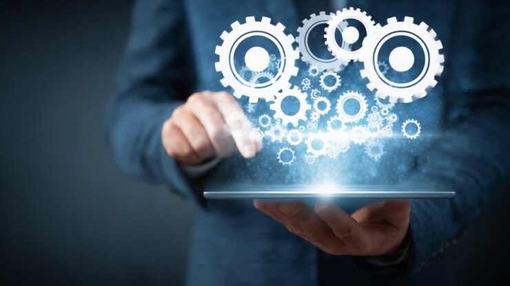 En professionel person med en tablet, der viser en visuel præsentation af tandhjul og teknologi, symboliserende innovation og digital integration i moderne forretningspraksis.