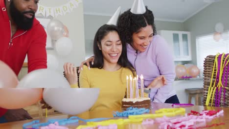 video of woman blowing out candles on birthday cake celebrating with diverse friends, in slow motion