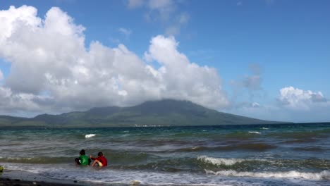 niños jugando en la playa con una hermosa montaña al fondo
