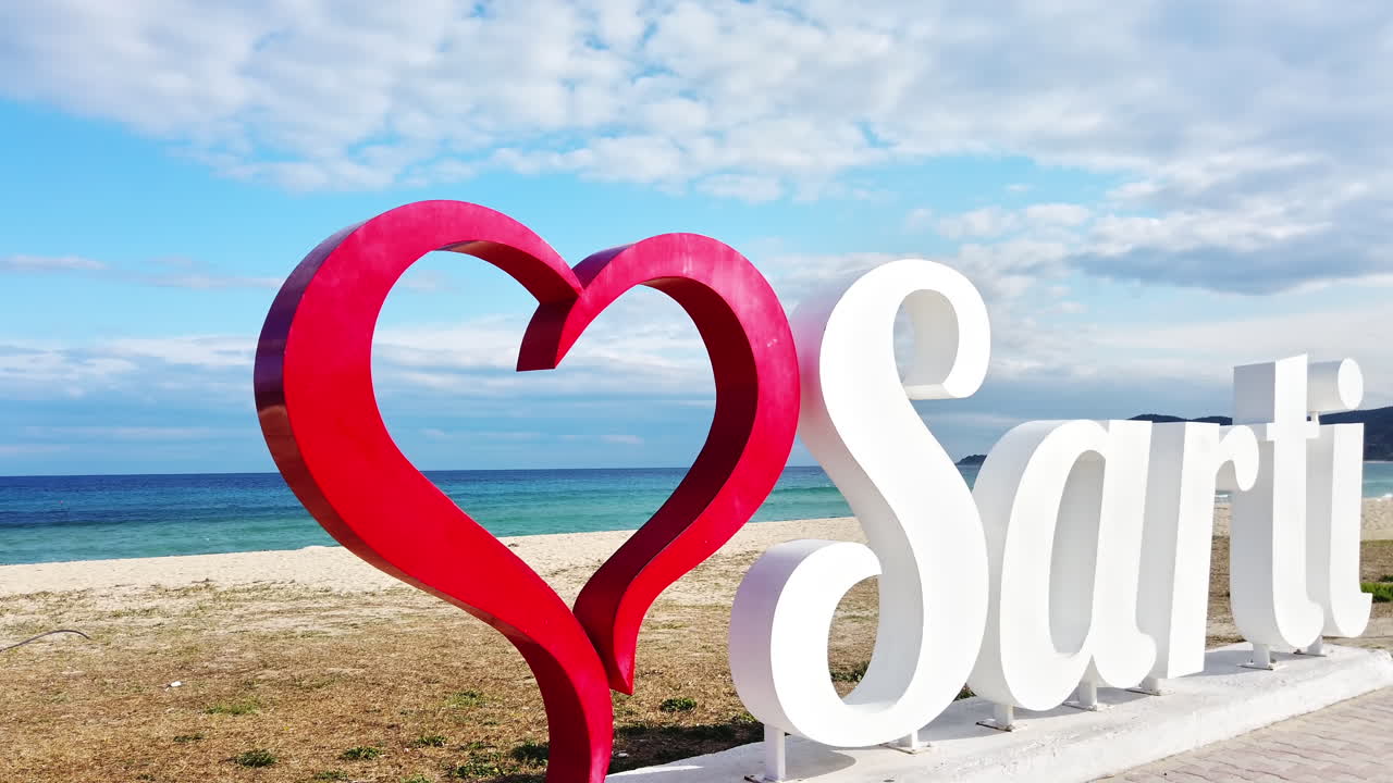 Sarti with red heart sign on the Aegean sea coast with water on the background, Greece. Slow motion