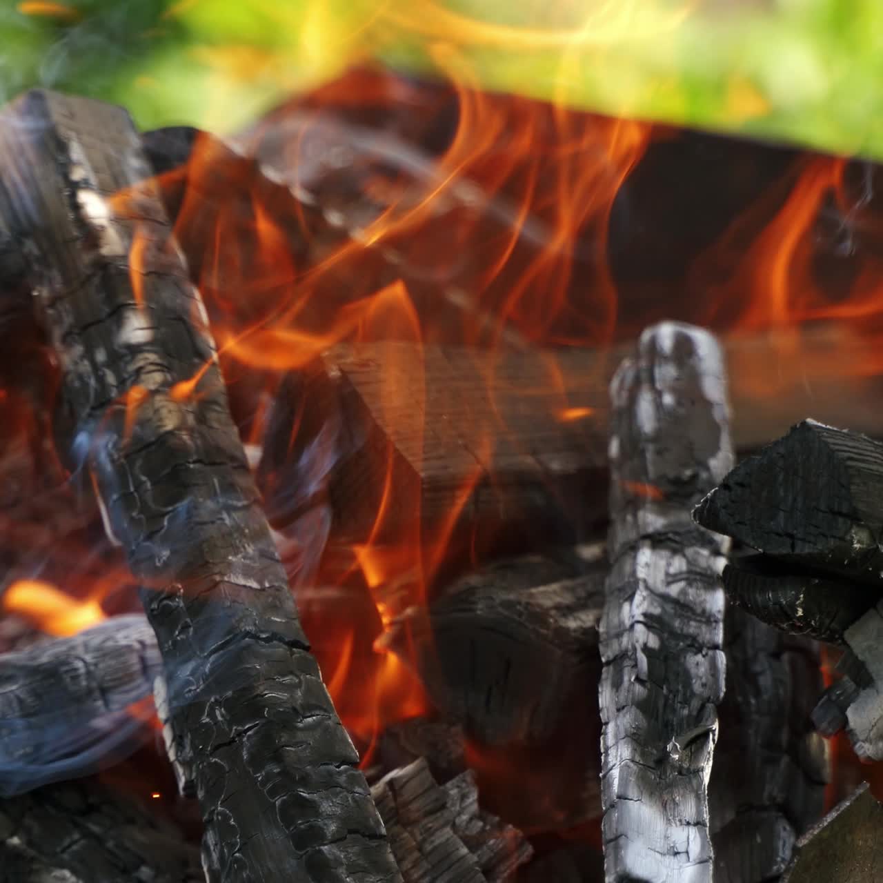 Hot charcoals in fire. Logs of wood smoldering and flaming. Wooden logs burning for barbeque outdoors.