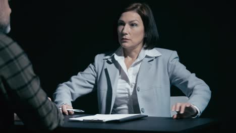 una detective agresiva comienza a interrogar a un sospechoso masculino sobre un crimen.