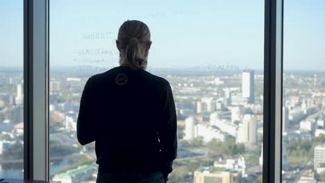 hombre mirando una vista de la ciudad desde una ventana de gran altura