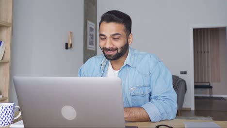 young happy attractive indian man having video call at home office using pc.