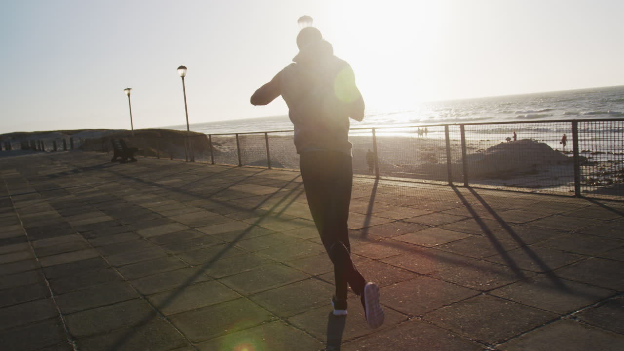 Focused african american man boxing and running, exercising outdoors by the sea