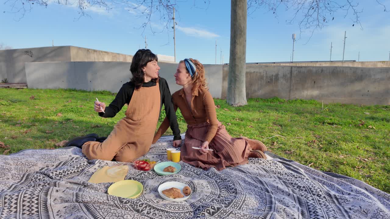 두 여인이 공원에서 피크닉을 즐기고 있다