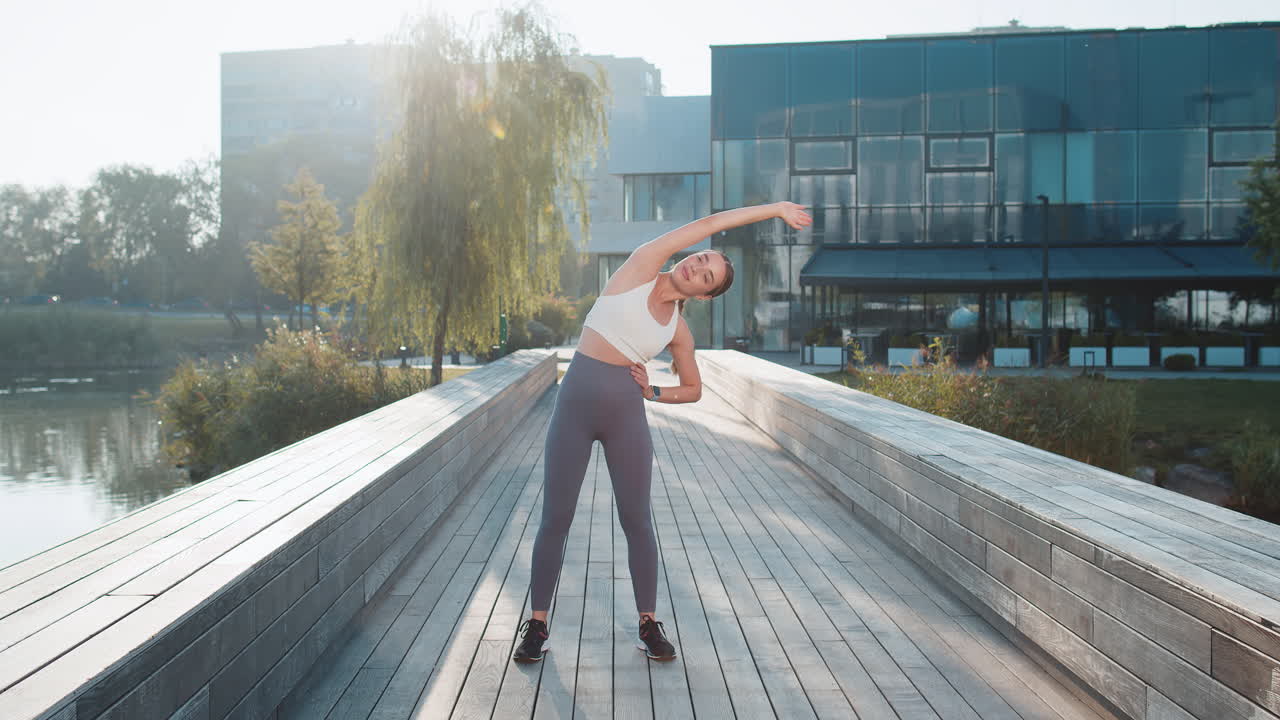 적합 한 젊은 여성 달리기 선수 는 운동 전 에 몸 을 히고 도시 공원 에서 야외 조 을 준비 하고 있다