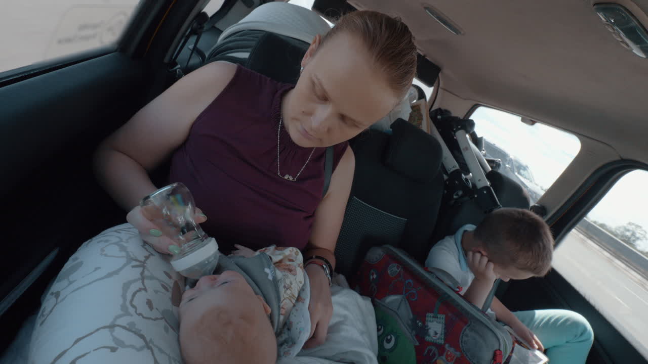 아기 와 장남 이 있는 여자 가 차 로 여행 하고 있다