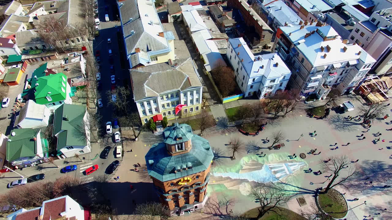 Square with a tower in the city park. Lots of people walk on sunny daytime. Top view.