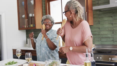 Felices-Amigas-Afroamericanas-Mayores-Preparando-Comida-Cantando-En-La-Cocina,-Cámara-Lenta