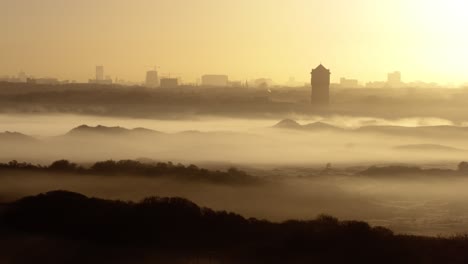 Drone-riser-of-foggy-dunes-with-Den-Haag-on-horizon