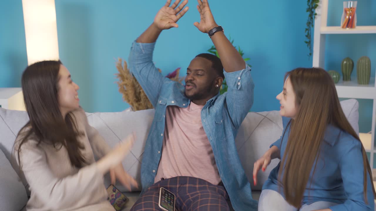 jóvenes de diferentes etnias mirando el teléfono en casa. se regocijan.