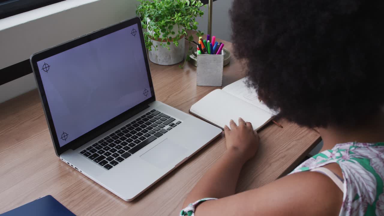 mujer de negocios afroamericana en videollamada, tomando notas, usando una computadora portátil con espacio de copia en la pantalla
