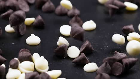 a close-up view of dark and white chocolate chips scattered on a black background.