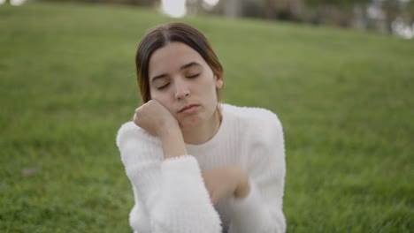 woman sitting in a park looking unhappy