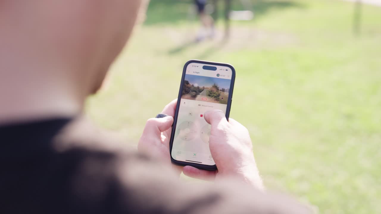 Over shoulder shot of male use smartphone to remote control drone, Czechia
