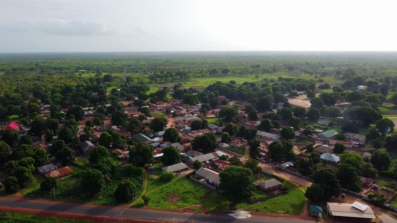 Luftfoto af en afrikansk landlig skovklædt landsby med asfalteret vej i Gambia nær Jufureh.