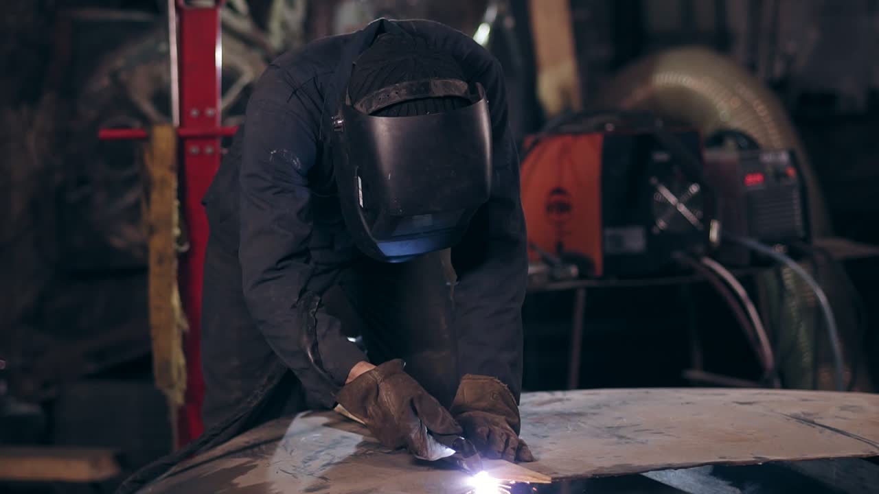 Unrecognizable workman all equiped with protective wear cuts piece of mettal with an industrial cutting torch