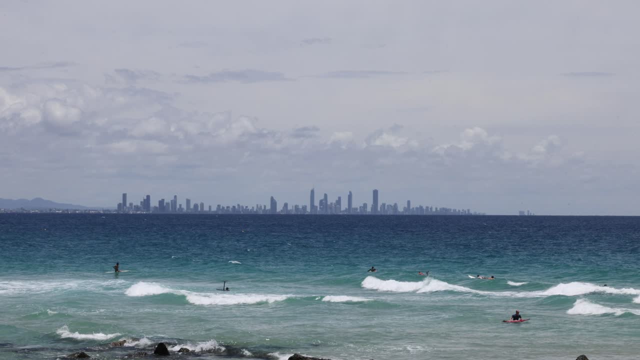 서퍼 들 과 파도 들 과 함께 도시 의 스카이 라인 을 배경 으로
