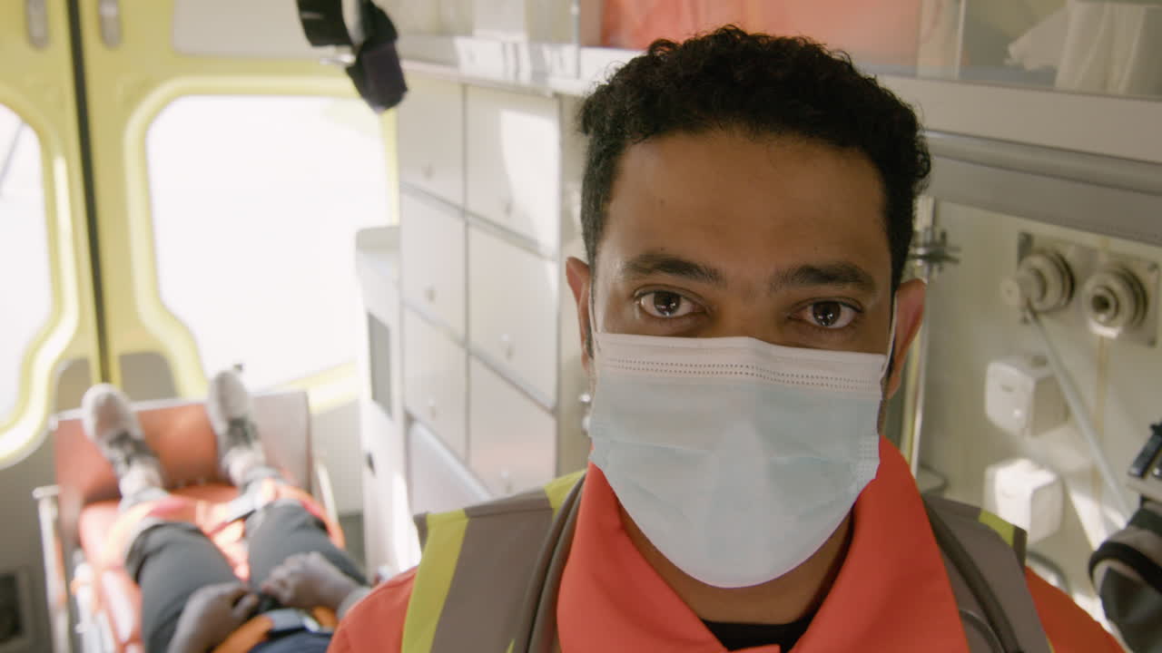 구급차를 타고 카메라를 바라보는 안면 마스크를 쓴 남성 구급대원의 초상화