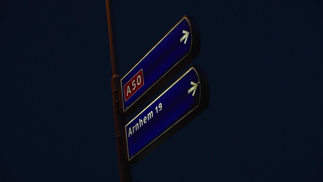 Night view of road signs indicating direction to Arnhem via A50