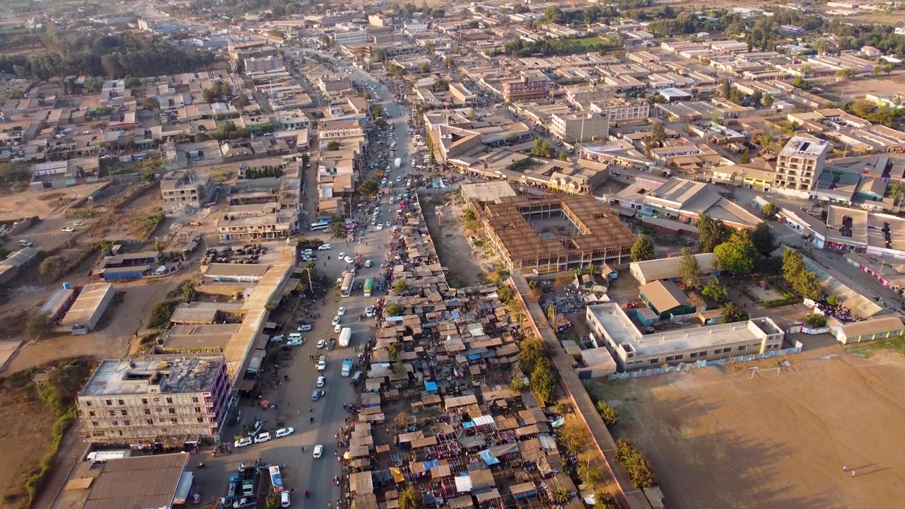 Splendida vista aerea di un mercato africano all'aperto con ombrelloni colorati, bancarelle affollate e gente del posto che commercia prodotti freschi sotto la calda luce del sole in Kenya.