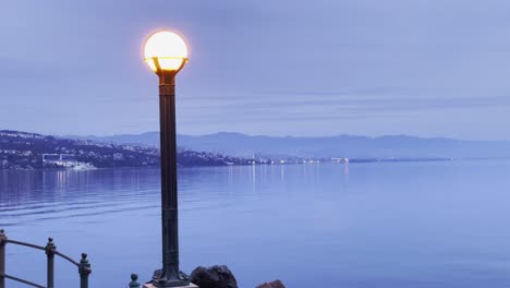luz de paseo marítimo en la orilla del mar con tierra en la distancia lovran, opatija, croacia