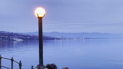 boardwalk light on sea shore with land in distance lovran, opatija, croatia